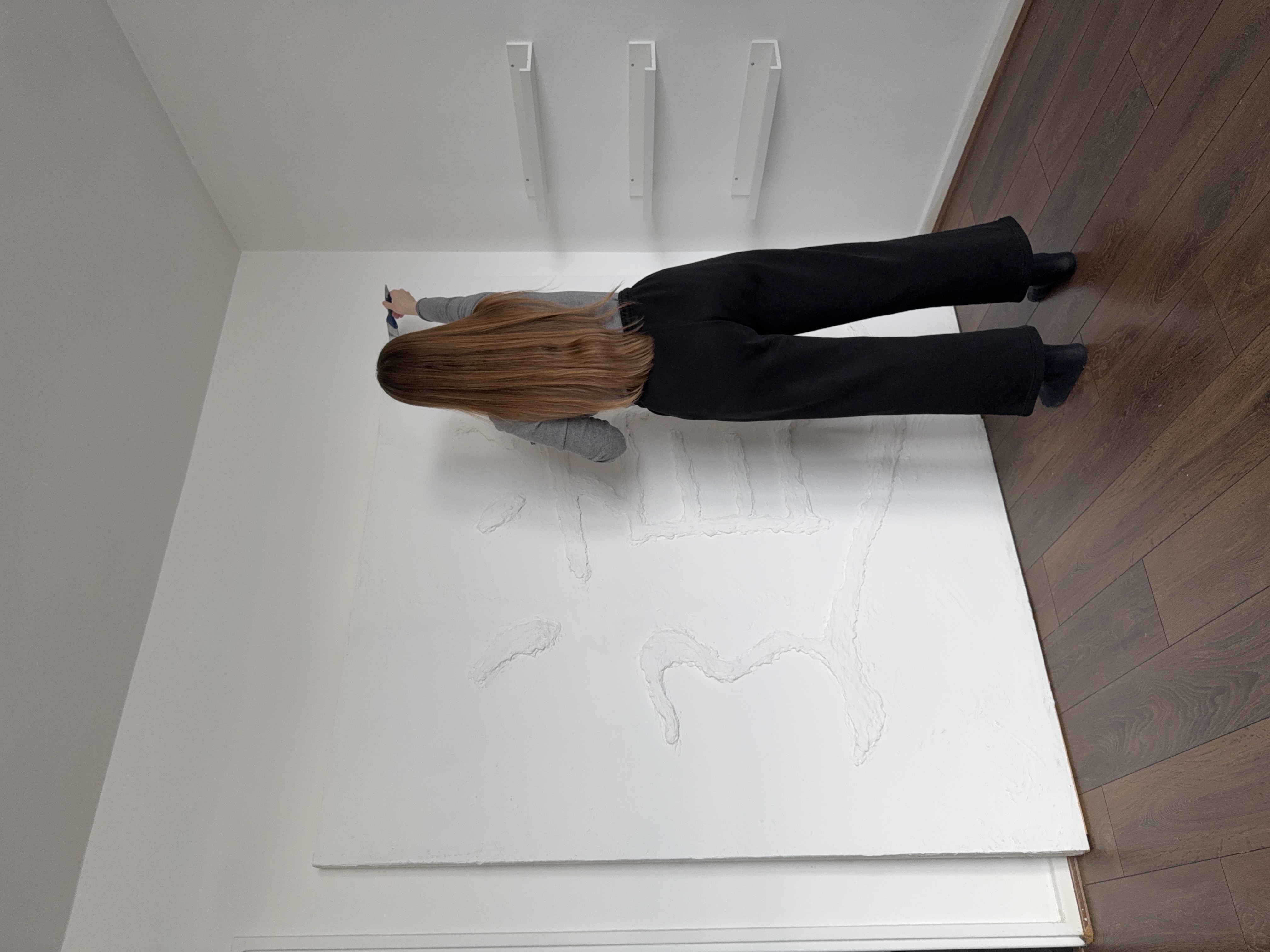 Artist Jenny Halseid standing beside the large Dao wall sculpture during the creation process.