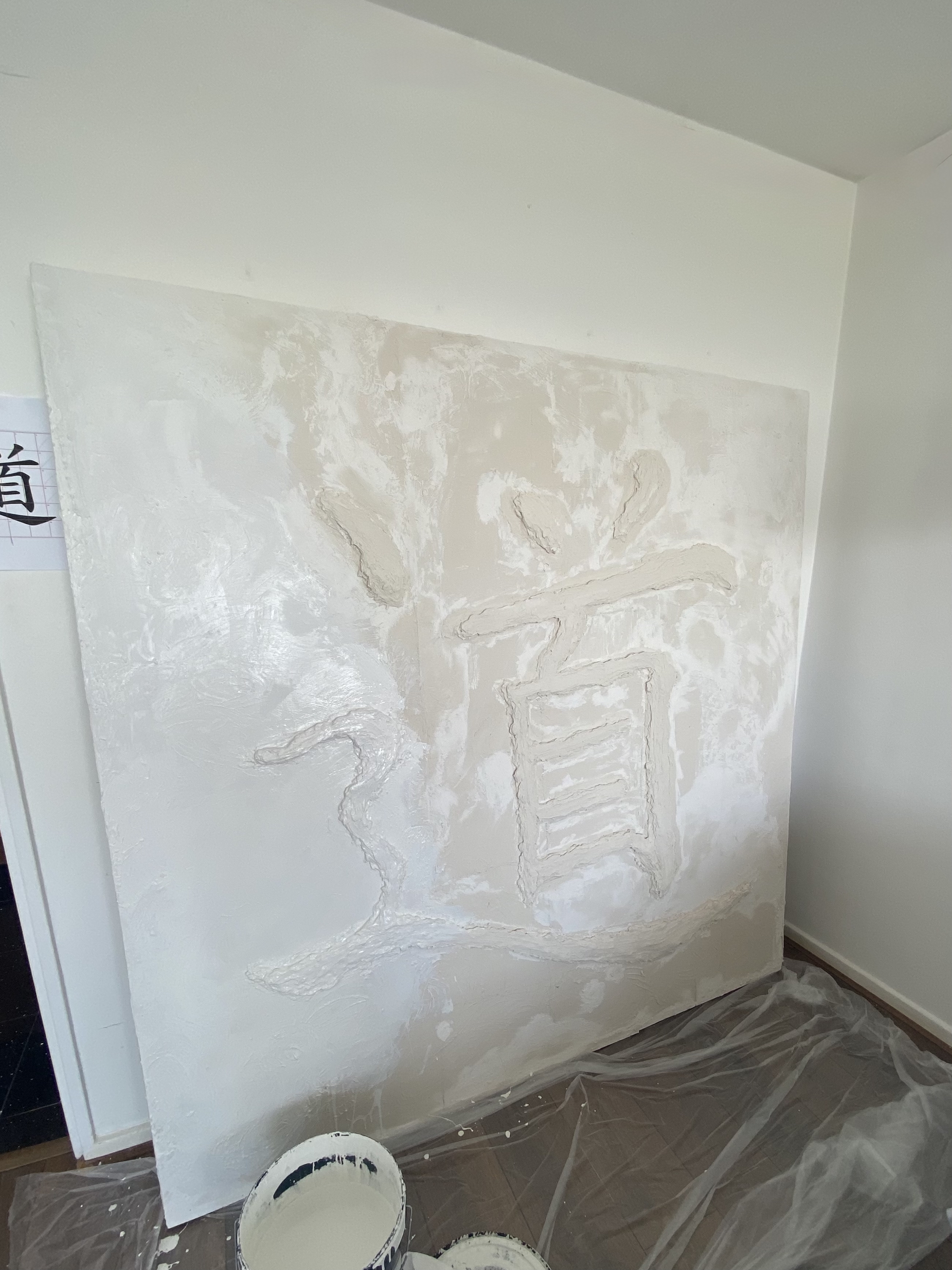 Partially completed Dao art piece with drywall mud applied to form the character on plywood panels.