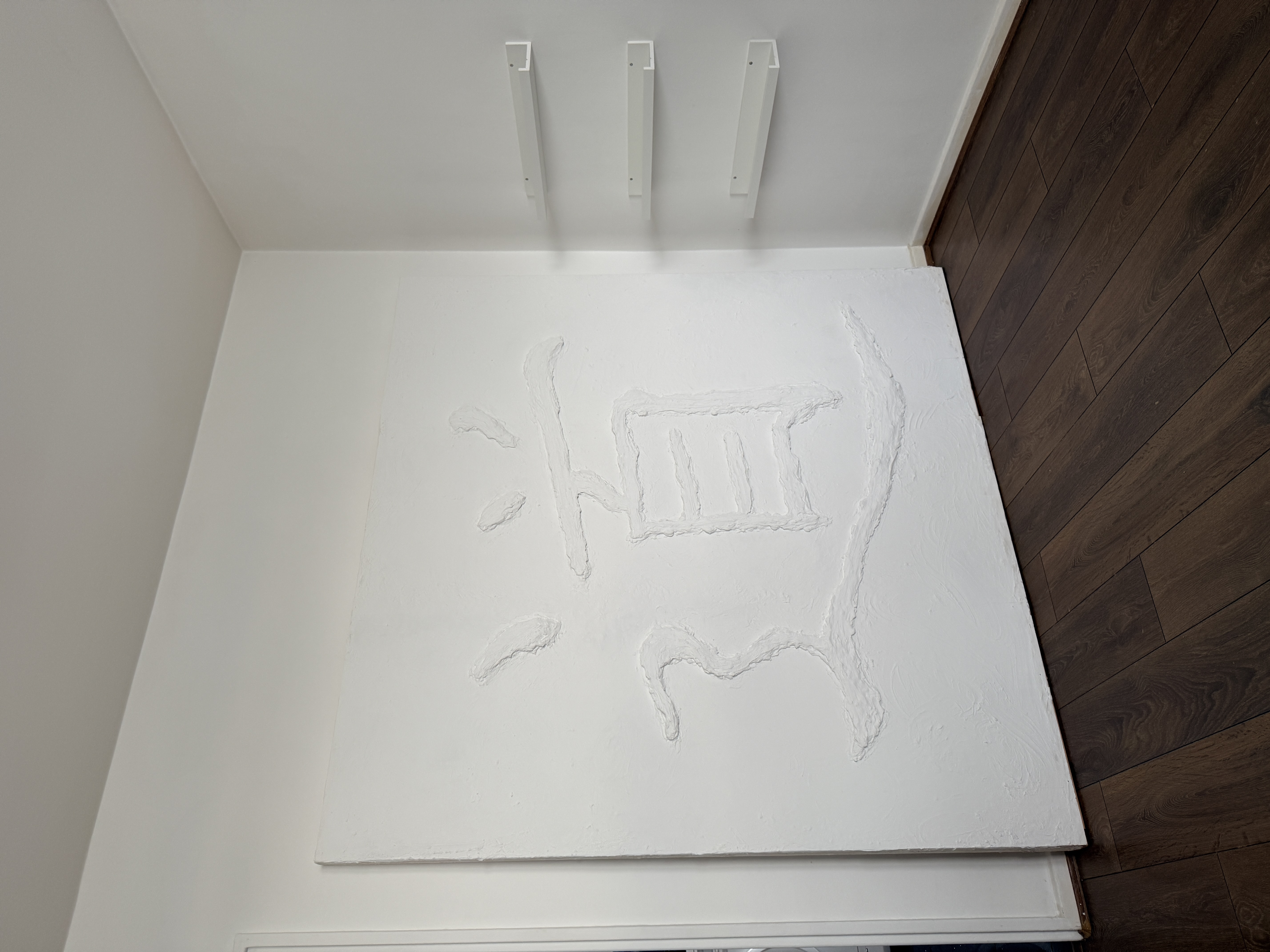 Wide side view of the Dao wall sculpture blending into a white interior space.